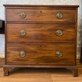 An early 19thC mahogany chest of drawers on bracket feet with brass handles.
