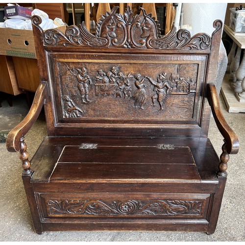 122 - A dark oak settle with deeply carved back and lift up seat. 107 w x 122 h x 58cm d.