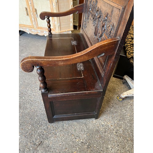 122 - A dark oak settle with deeply carved back and lift up seat. 107 w x 122 h x 58cm d.