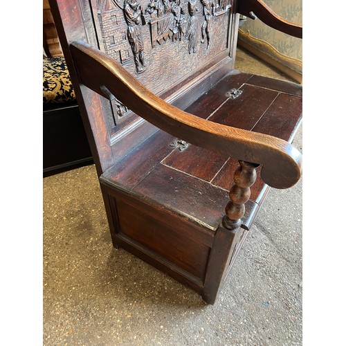 122 - A dark oak settle with deeply carved back and lift up seat. 107 w x 122 h x 58cm d.