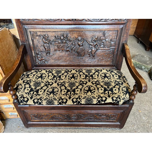 122 - A dark oak settle with deeply carved back and lift up seat. 107 w x 122 h x 58cm d.