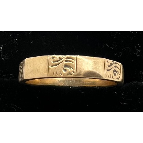 581 - A 9ct gold band. Weight 2.7gm. Size L with engraved decoration.