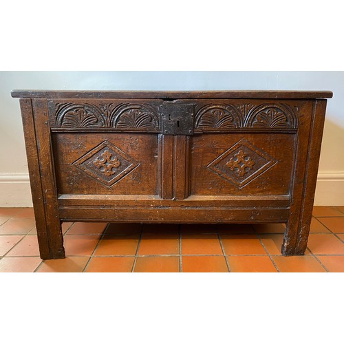 127 - A late 17thC/early 18thC small oak coffer with sunken two panel lid above carved frieze and carved p... 