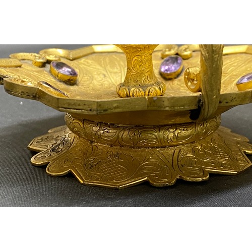 769 - A candlestick holder set with 5 purple coloured stones, centurion head decoration to handle. 11cm w ... 