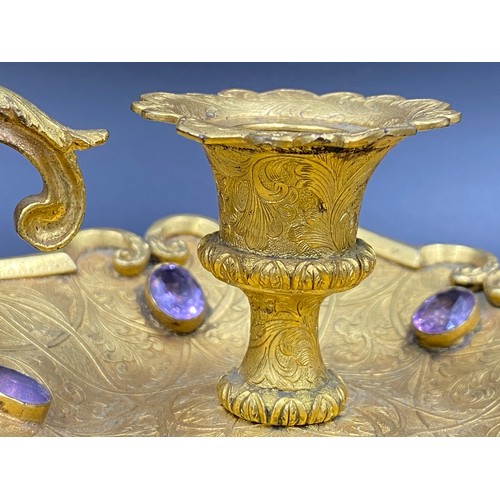 769 - A candlestick holder set with 5 purple coloured stones, centurion head decoration to handle. 11cm w ... 