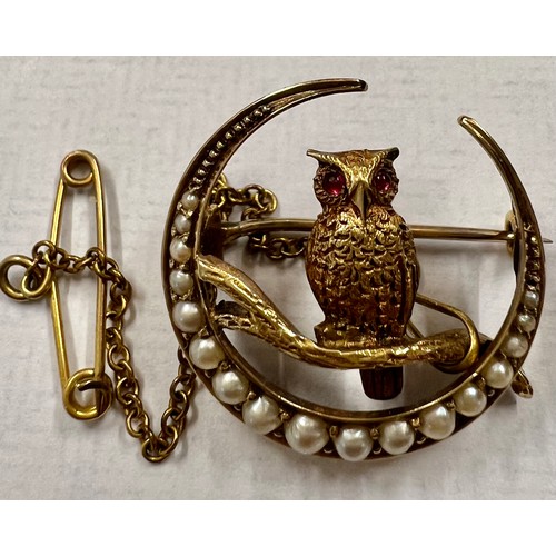 601 - A 15ct crescent shaped brooch with an owl on branch, set with seed pears and rubies with safety chai... 