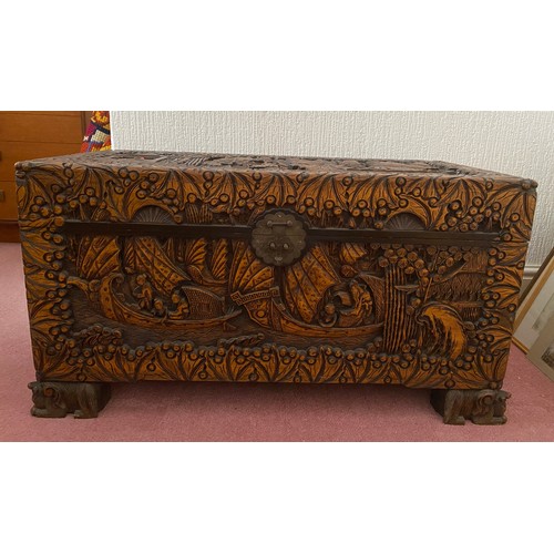 80 - A heavily carved oriental camphor wood chest raised on carved lions. Brass fastening to front. 96 w ... 