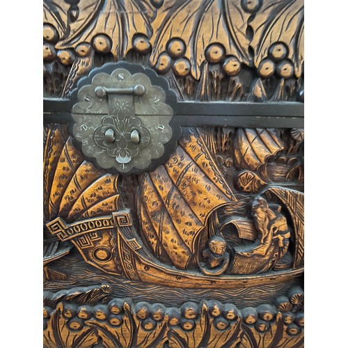 80 - A heavily carved oriental camphor wood chest raised on carved lions. Brass fastening to front. 96 w ... 