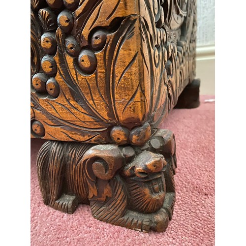 80 - A heavily carved oriental camphor wood chest raised on carved lions. Brass fastening to front. 96 w ... 