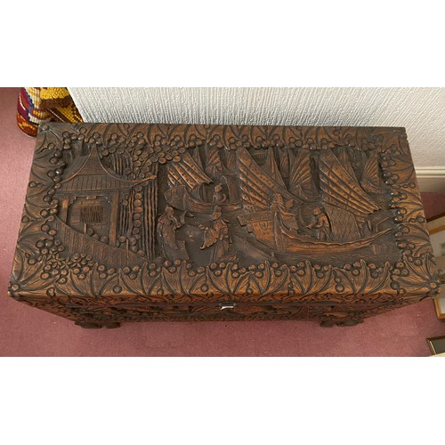 80 - A heavily carved oriental camphor wood chest raised on carved lions. Brass fastening to front. 96 w ... 