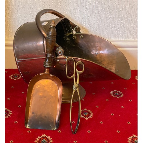 942 - A 19thC copper coal helmet with a copper and wooden shovel and brass tongs.