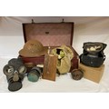 A suitcase containing 3 gas masks, two in original bags, WW II original helmet, eye shields, anti ga... 