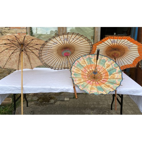 707 - Thee painted paper parasols, fabric umbrella and a spare umbrella handle.