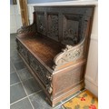 A dark oak continental carved panel backed settle. 107 h x 154 w x 55cm d.
