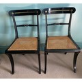 A pair of ebonised Trafalgar chairs maker N T Osbourne. Cane seats, brass inlay and sabre legs to fr... 