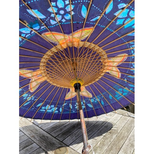 704 - A Japanese blue painted parasol, early 20thC, with a bamboo shaft, painted with 4 butterflies with a... 