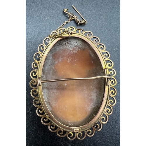 548 - A carved shell cameo brooch in a 9ct gold mount with safety chain 6 x 4.5cm. Total weight 18gm.