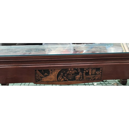 16 - Oriental glass topped table measuring 102 l x 51 d x 41.5cm h with carvings to top sides and ends.