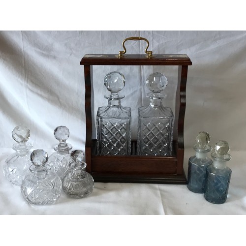 421 - An open wooden tantalus 37 h x 17cm w holding two cut glass decanters with stoppers 26 h x 10cm w al... 