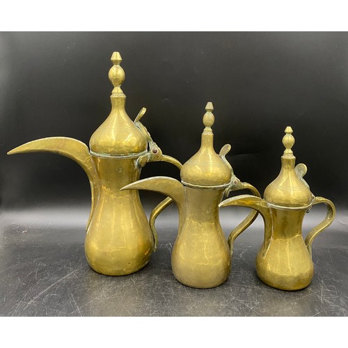 944 - Three graduating Middle Eastern brass coffee pots. Tallest 37cm.