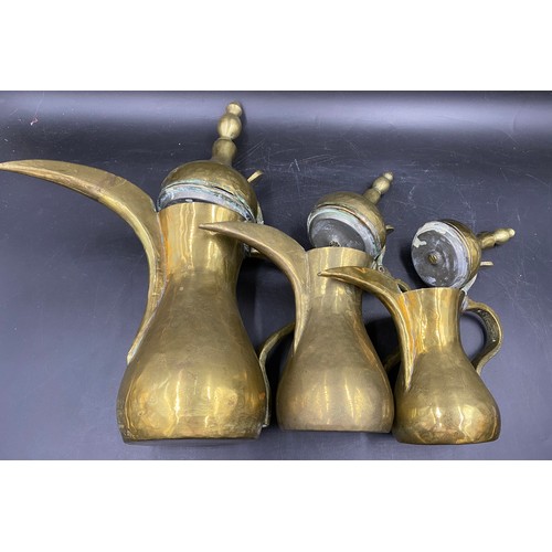 944 - Three graduating Middle Eastern brass coffee pots. Tallest 37cm.