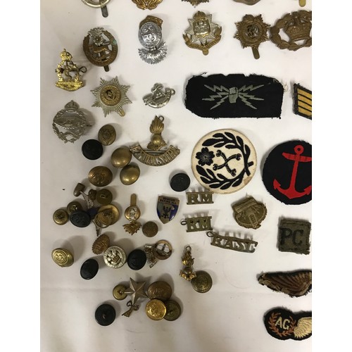 1202 - A collection of WWI and WW2 cap badges and shoulder titles to include RAF, Royal Navy, Japanese etc ... 