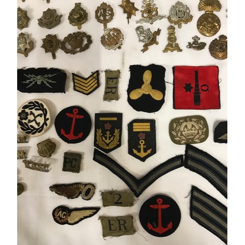 1202 - A collection of WWI and WW2 cap badges and shoulder titles to include RAF, Royal Navy, Japanese etc ... 