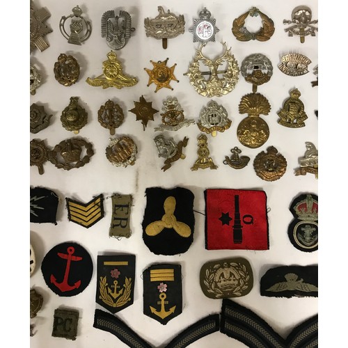 1202 - A collection of WWI and WW2 cap badges and shoulder titles to include RAF, Royal Navy, Japanese etc ... 