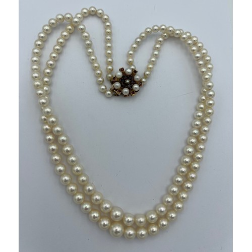 583 - Double strand cultured pearl necklace with pearl and garnet set clasp. Approximately 48cm length.