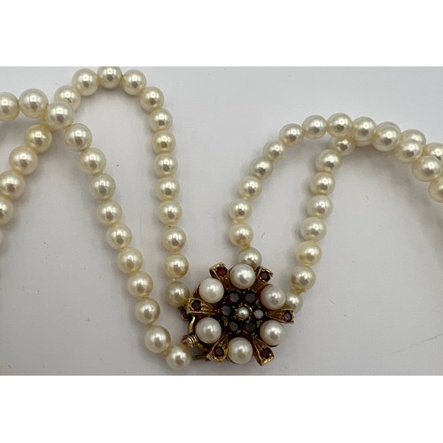 583 - Double strand cultured pearl necklace with pearl and garnet set clasp. Approximately 48cm length.