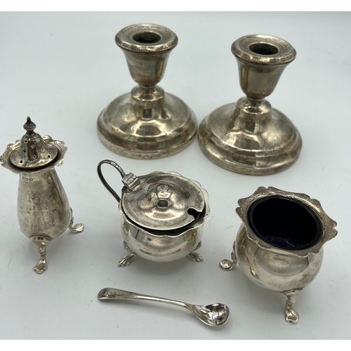 737 - Silver to include three-piece cruet, mustard spoon and a pair of candlesticks with weighted bases, B... 