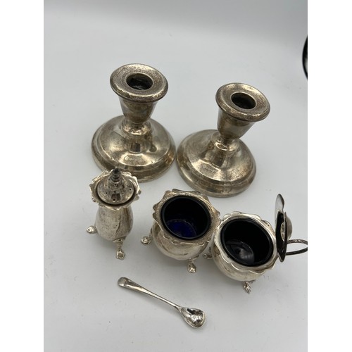 737 - Silver to include three-piece cruet, mustard spoon and a pair of candlesticks with weighted bases, B... 