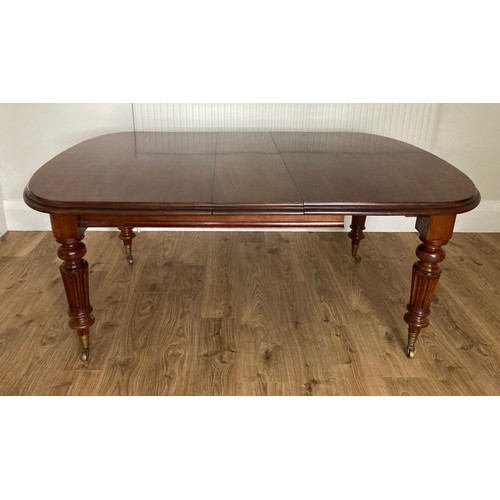 85 - A 19thC mahogany wind out dining table on fluted tapering legs and brass castors. 76 h x 121 w x 148... 