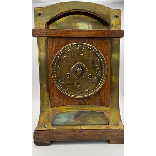 1192 - An Arts and Crafts oak and brass mantle clock. Probably Liberty. 37h x 25 w.