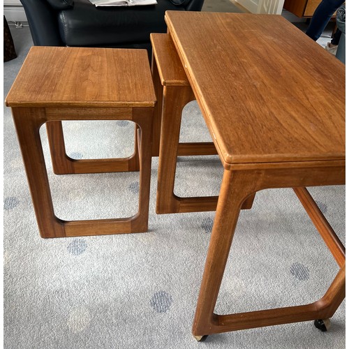 115 - A nest of 3 mid-century teak tables to include one fold over opening to form a larger table 81 x 76c... 