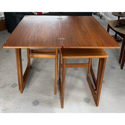 115 - A nest of 3 mid-century teak tables to include one fold over opening to form a larger table 81 x 76c... 