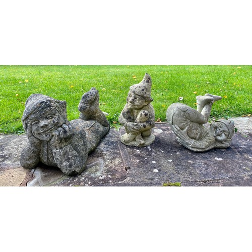 231 - Three garden ornaments of pixies with crossed legs. Recumbent pixie 50 l x 29cm h.