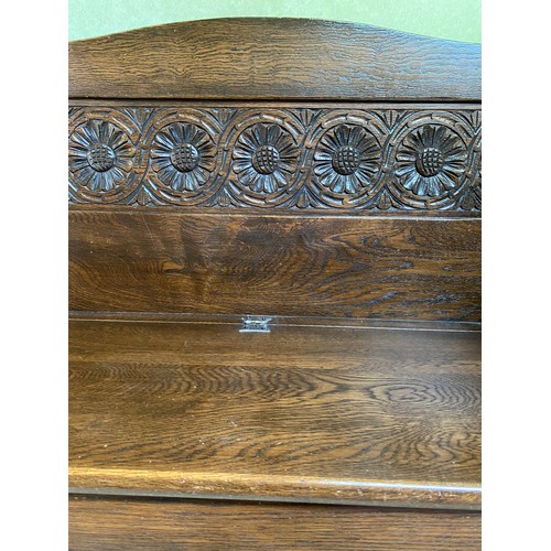 144 - A carved oak monks bench with lift up seat. Height to back 90cm h x 106cm w  x 41cm d.