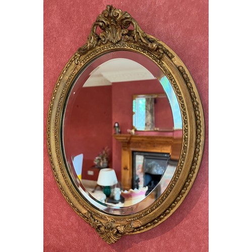 1138 - Two gilt oval wall mirrors, largest with bow 59cm h x 39cm w, smaller bevel edged 33cm h x 24.5cm w.