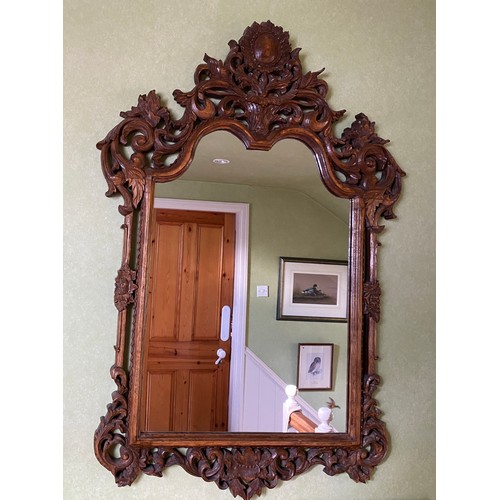 1142 - A decorative carved oak wall mirror.