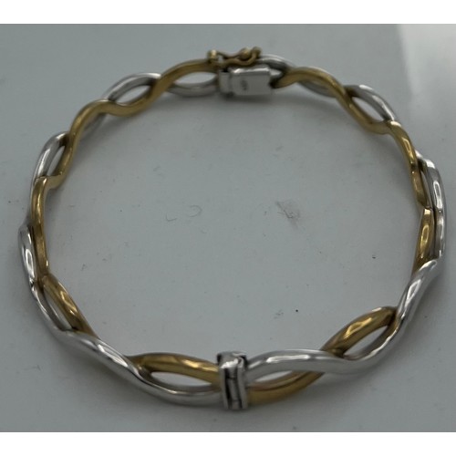 611 - A nine carat yellow and white gold hinged bangle. Weight 10.6gm.