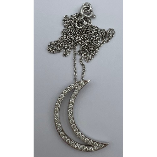 620 - An 18 carat white gold crescent moon pendant, 2.2cm top to bottom set with diamonds on a fine chain ... 