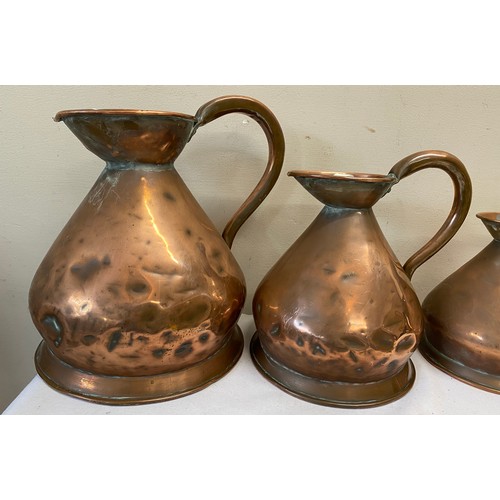 1059 - Three graduated copper measures together with a copper tankard. Largest jug 28cm h.