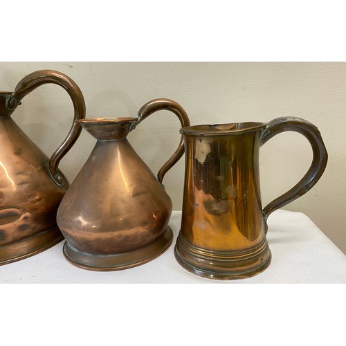 1059 - Three graduated copper measures together with a copper tankard. Largest jug 28cm h.