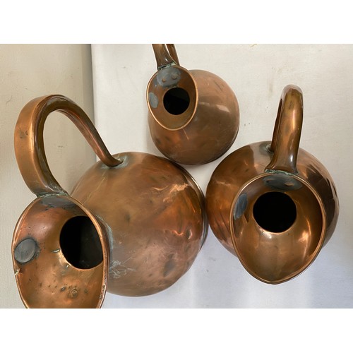 1059 - Three graduated copper measures together with a copper tankard. Largest jug 28cm h.