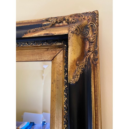 1150 - A modern black and gilt bevelled edge wall mirror 80 h x 110cm w.