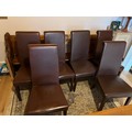 Six high back brown leather upholstered dining chairs on square tapered legs.