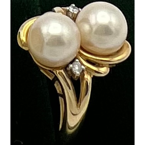 506 - A 14 carat yellow gold ring set with two cultured pearls and two diamonds. Weight 4gm. Size L.