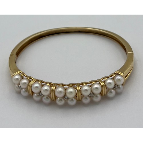 501 - A fourteen carat yellow gold bangle set with pearls and diamonds. Total weight 17.6gm.