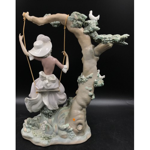 235 - Lladro porcelain figure - Woman on a swing with a dog and small doves. 38cm high.